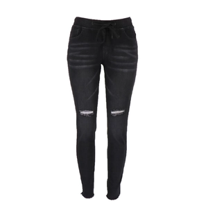 Détail d'un jean slim noir avec genoux déchirés et taille élastique ajustable à cordon