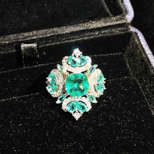 Micro-paved ring featuring a large emerald-cut green gemstone in a dark velvet box