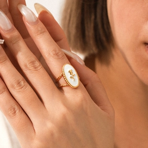 Detailed close-up of a golden rose enamel ring on model featuring vintage white drip oil inlay