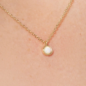 Macro shot of minimalist gold S925 silver necklace with white opal pendant on skin
