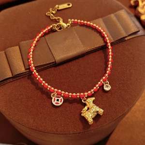 Close-up of 18K gold-plated zodiac dog charm with red woven cord and crystal pendant