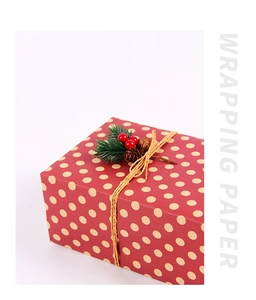 Detail of red polka dot Christmas gift wrap with jute twine, pine cones and berries