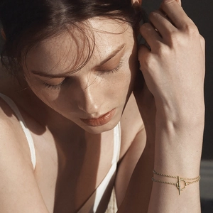 Detail of a double-layered gold bracelet with a toggle clasp worn on a female wrist