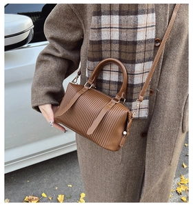 Detailed texture of brown pleated faux leather pillow bag with elegant top handles