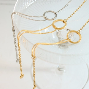 Minimalist ring pendant chain bracelet in gold and silver on a textured glass tray