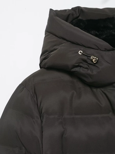 Detail of hooded jacket featuring matte black fabric, faux fur lining, and gold toggles