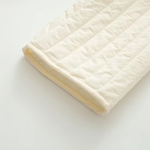 Close-up of quilted cream cotton jacket showing premium fabric texture and padded stitching