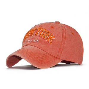Detail of orange washed cotton baseball cap featuring 3D New York embroidery
