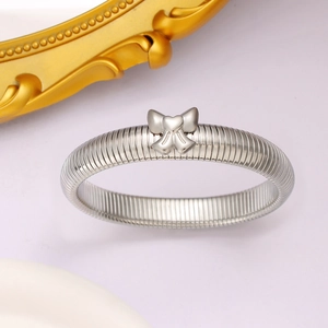 Gros plan d'un bracelet torsadé en acier argenté avec un pendentif cœur et nœud