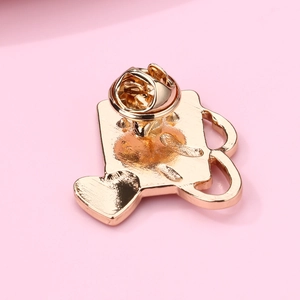 Macro shot of gold watering can brooch back showing secure pin and butterfly clutch