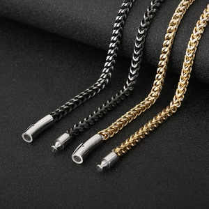 Macro detail of gold and gunmetal wheat chains with mechanical clasps on matte background