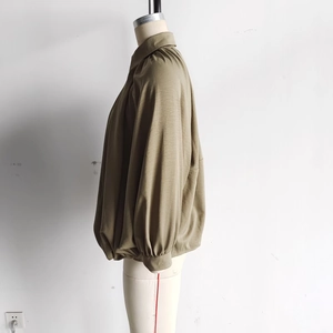 Detail of puffed lantern sleeves and pleated texture on brown long-sleeve bomber jacket