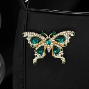 Vintage gold butterfly brooch with emerald green crystals on black leather bag