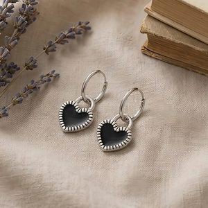 Macro detail of heart-shaped hoop earrings with black enamel inlay and sunburst engraving