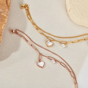 Detail of double-layer stainless steel heart pearl bracelet in gold and rose gold
