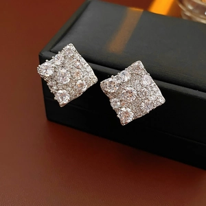 Vue macro de boucles d'oreilles géométriques en forme de losange serties de zircons