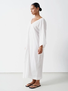 Detail of the deep V-neck and lace-up sleeve on white cotton loose maxi dress