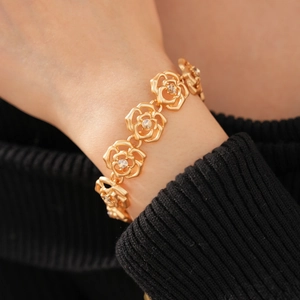 Detailed view of elegant gold hollow rose bracelet with crystal rhinestones on a wrist