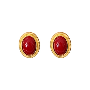 Vintage gold twisted rope earrings set with oval red gemstones on a white background