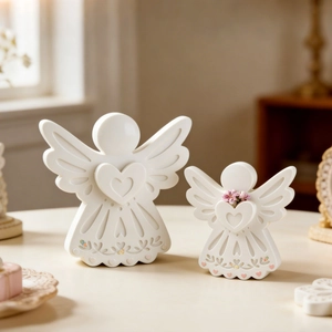 Detail of white ceramic angel figurines with heart cutouts and floral accents in a home setting