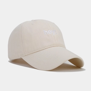 Close-up of white hey letter embroidery on beige cotton twill baseball cap with curved brim