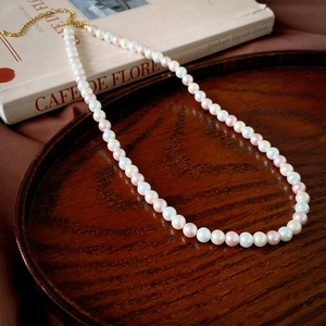 Vue détaillée du collier de perles rose et blanc avec fermoir doré sur plateau