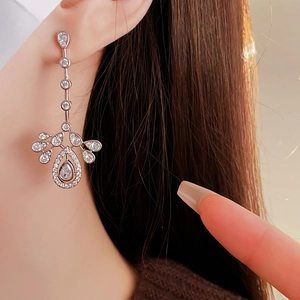 Macro detail of silver tassel earrings with clear zircon teardrop and leaf design charms