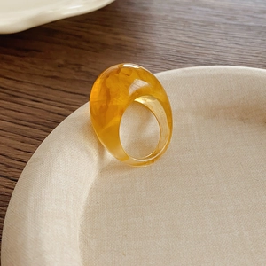 Détail d'une bague en résine ambre avec texture nuageuse et finition brillante