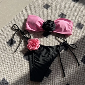 Detailed flat lay of bikini set with 3D fabric roses on bandeau top and side-tie bottoms