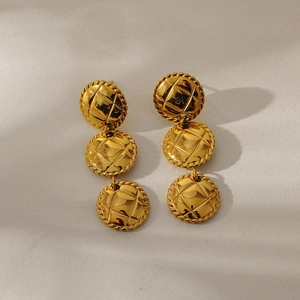 Detail of gold geometric drop earrings with three-layer textured round disks