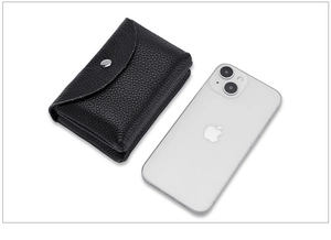 Close-up of black pebble grain leather coin purse with snap button next to a smartphone