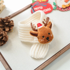Detailed texture of white knit Christmas pet scarf featuring cute reindeer antler decor