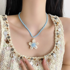 Collana bohémien con perline azzurre e pendente a fiore in conchiglia su modella