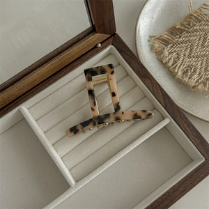 Detail view of a vintage leopard acetate hair claw clip inside a wooden jewelry box