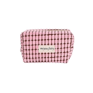 Pink waffle knit makeup bag with zipper and minimalist fabric brand label on white background