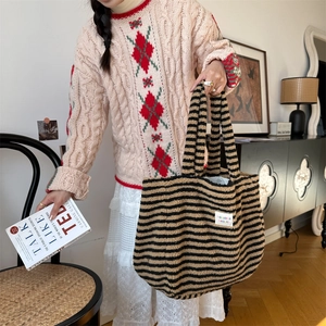 Detail of plush tote bag with brown and black stripes shown in a cozy lifestyle setting