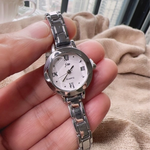 Detail shot of a silver small dial quartz watch with roman numerals on a metal strap