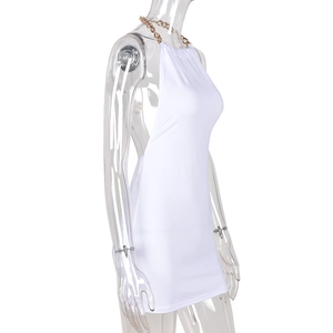 Détail d'une mini robe blanche moulante avec chaîne dorée et dos nu licou élégant