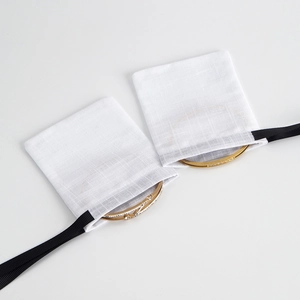 Detail of gold bracelets with sparkling crystals in white cotton drawstring jewelry pouches