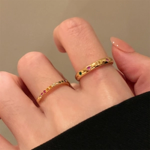 Primo piano di anelli a esagramma dorati con zirconi multicolore indossati sulle dita