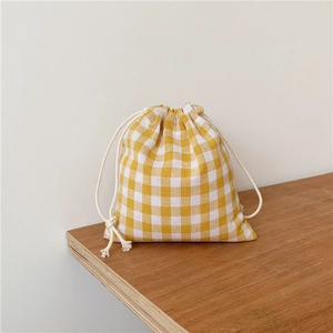 Close-up of yellow plaid linen drawstring bag on a rustic wooden table surface