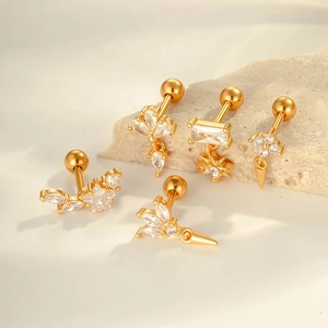 Set of 5 golden geometric ear studs with zircons on stone and fabric background