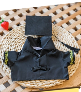 Detail view of miniature black doll graduation gown with yellow patterns and matching tassel cap