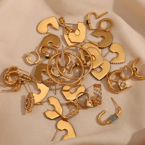 Detail shot of assorted 18K gold plated C-shaped geometric earrings on beige velvet fabric
