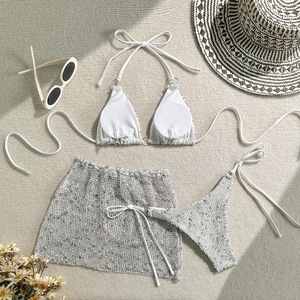 Flat lay of a 3-piece mesh bikini set with metal rings and a matching sarong skirt
