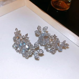 Macro view of crystal encrusted flower and leaf ear cuffs on a velvet jewelry tray