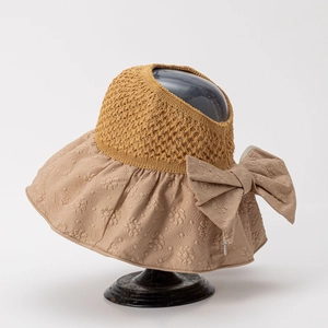 Detail of sun visor showing yellow crochet top, khaki brim, and large bow decoration
