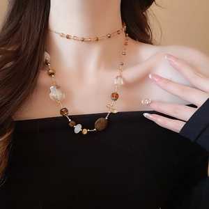 Dettaglio di una collana a doppio strato con perle ambra e bianche su una modella