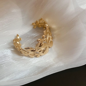 Détail d'un bracelet papillon doré sur un fond en tissu blanc doux avec une lumière chaude
