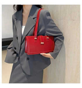 Detail of red leather rectangular bag with gold metal buckle on a grey suit model
